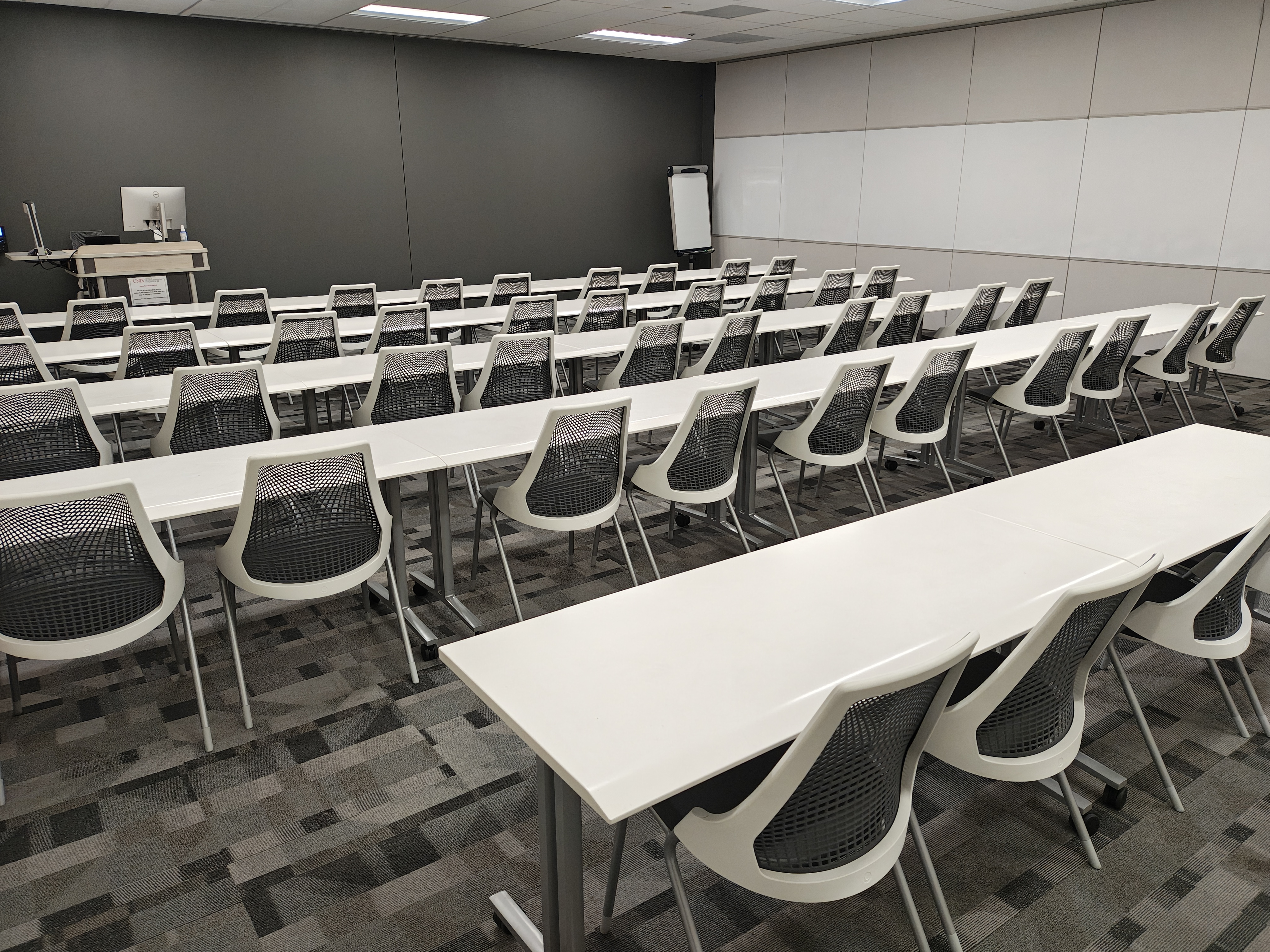 Empty classroom with rows of chairs and tables, and a lectern 