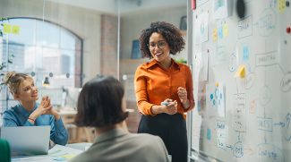 woman at a whiteboard demonstrating a product lifecycle.